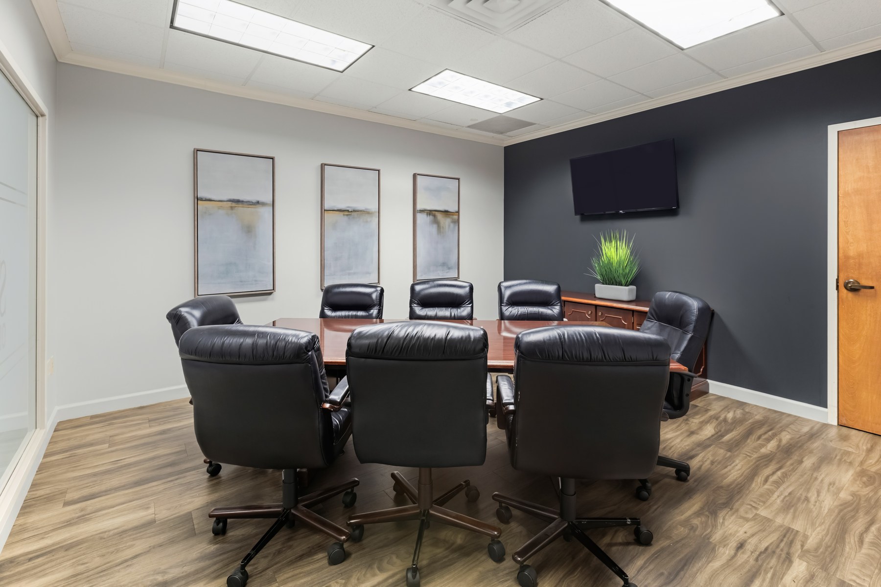Conference room at Scenic Office Suites with wall-mounted TV and seating for eight